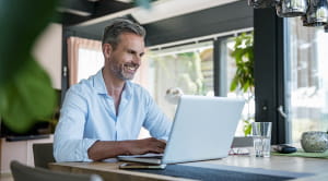 Working from home; man smiling with laptop